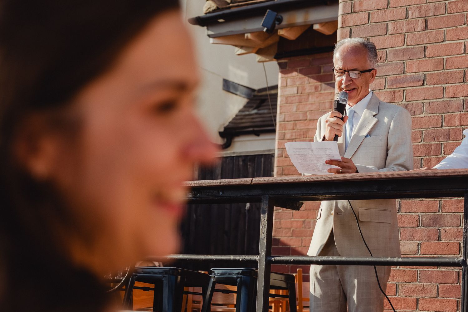 A group of people gather at a brick-walled venue for a social event with drinks and conversation.