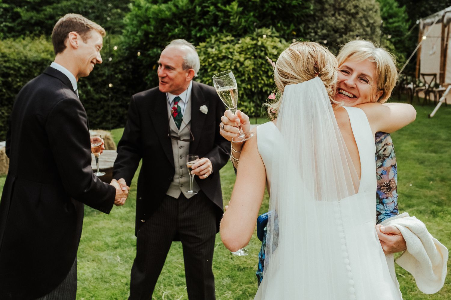 Candid moment of celebration in garden during wedding reception.