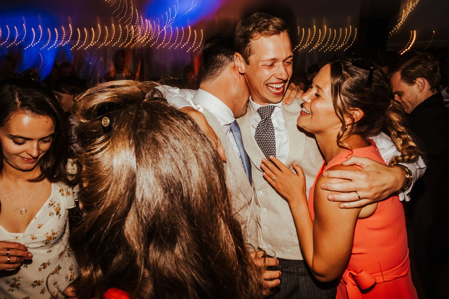 Candid moment of guests laughing and celebrating during wedding reception party.