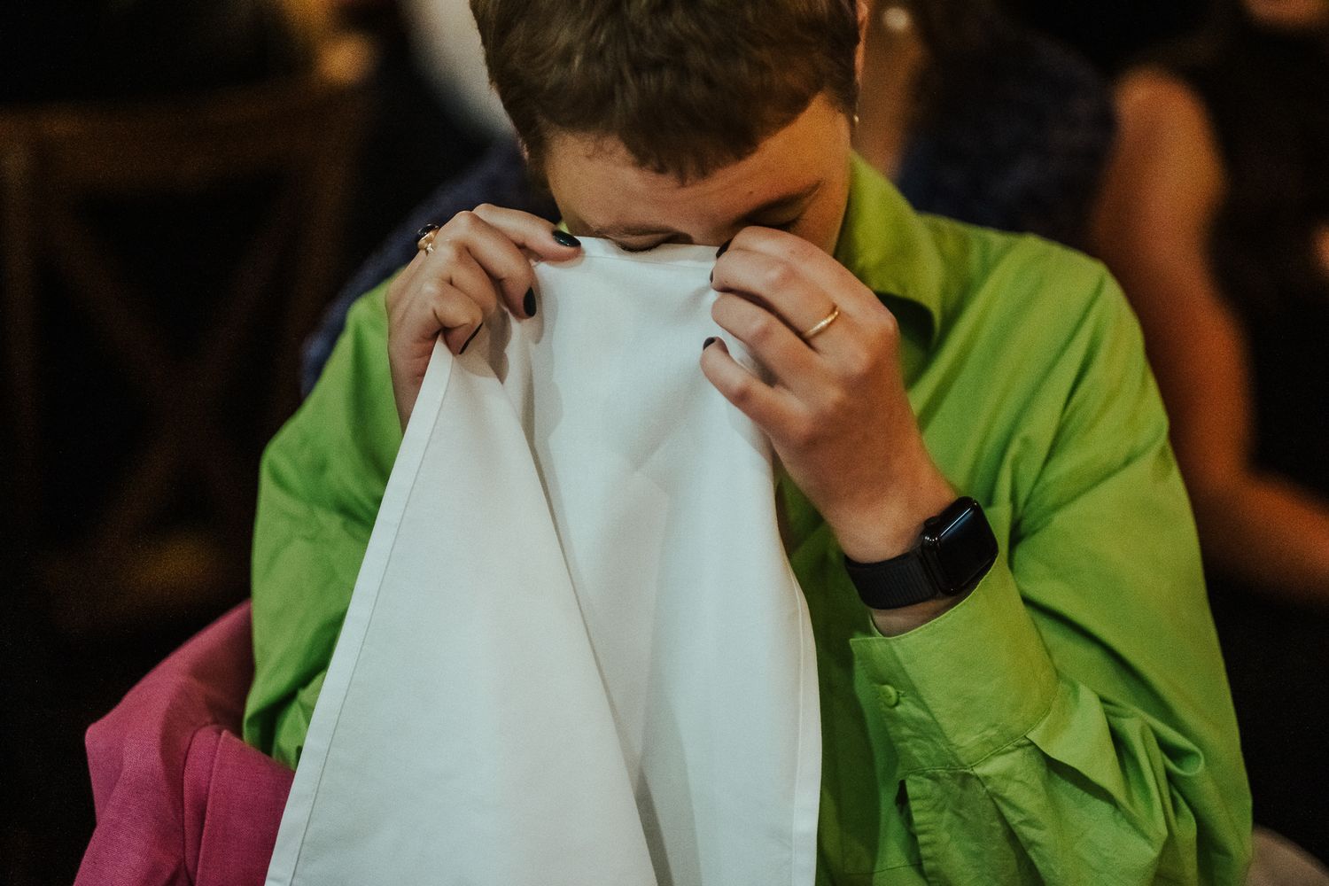 Someone in a bright green outfit wipes tears with a napkin during an emotional moment.