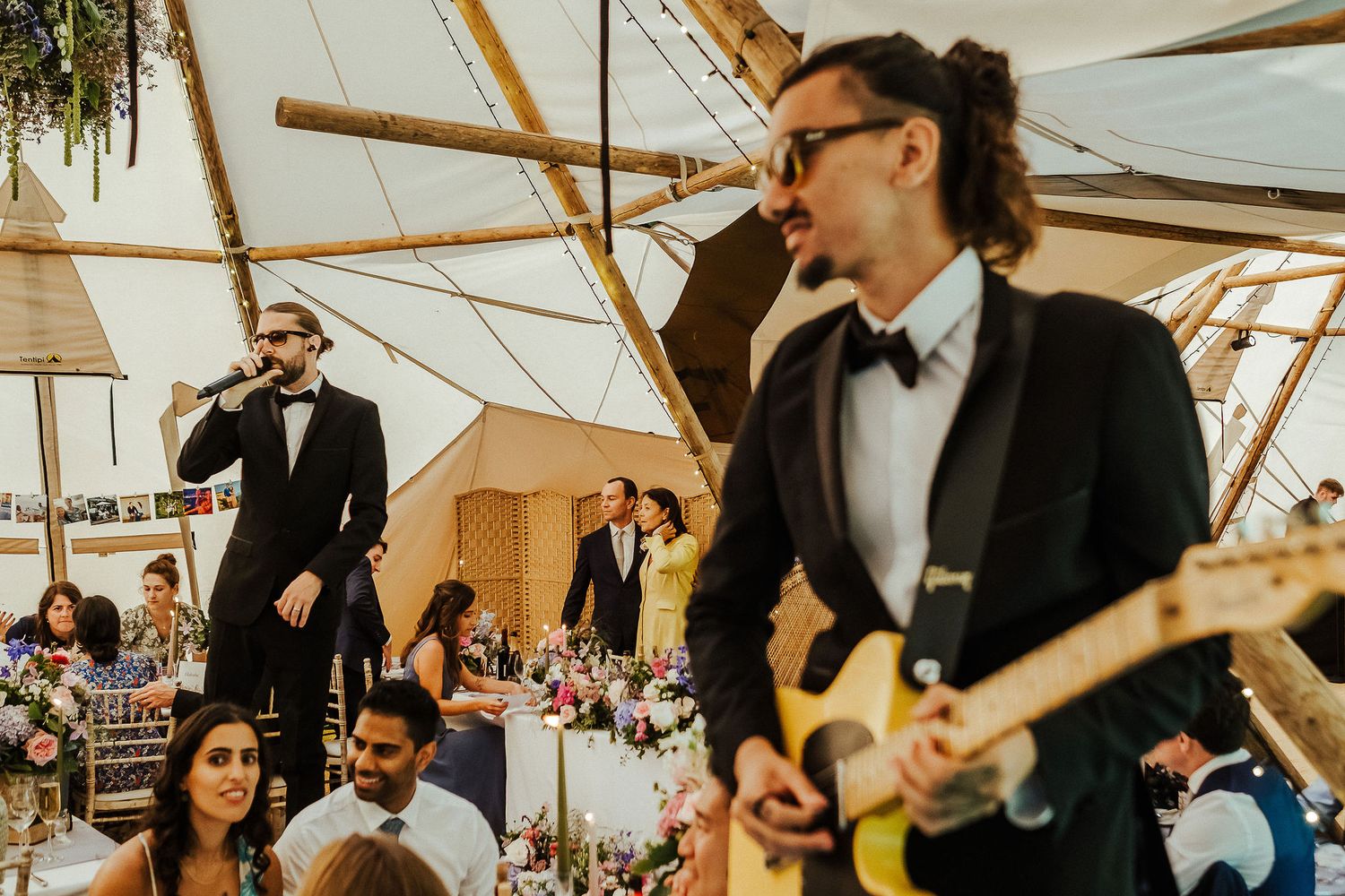 Candid moments captured during a wedding reception inside an elegantly lit tent structure.