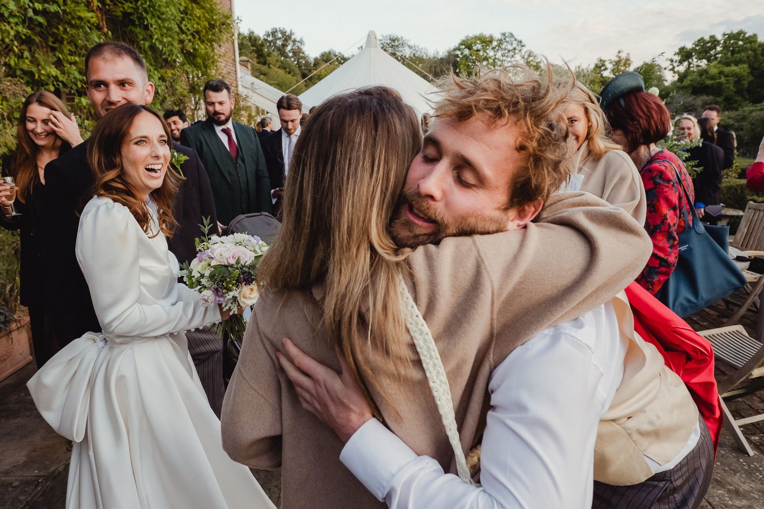 Wedding guests celebrate and dance together at an outdoor reception party during sunset.