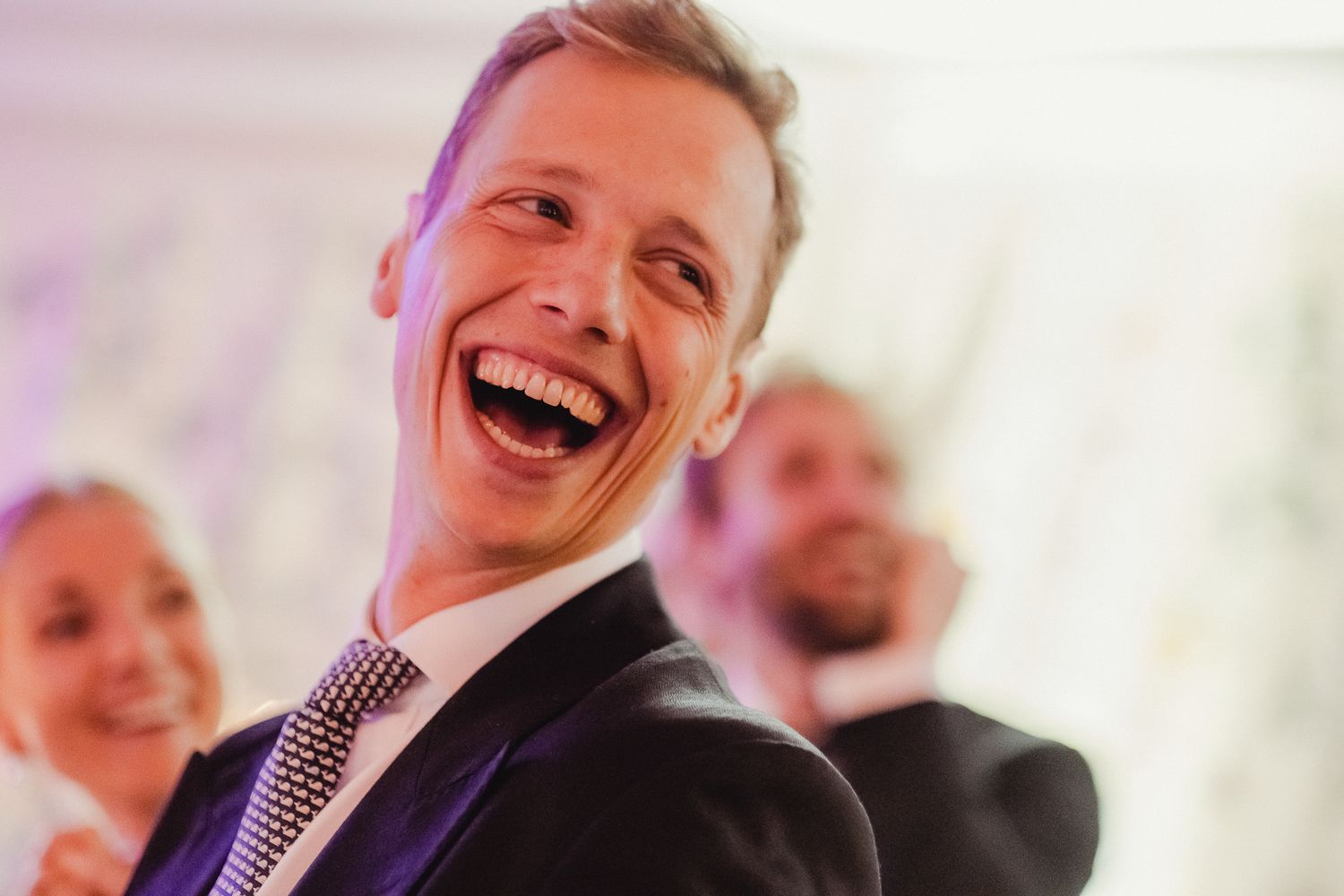 A group of people share a joyful moment of laughter together at what appears to be a social gathering.
