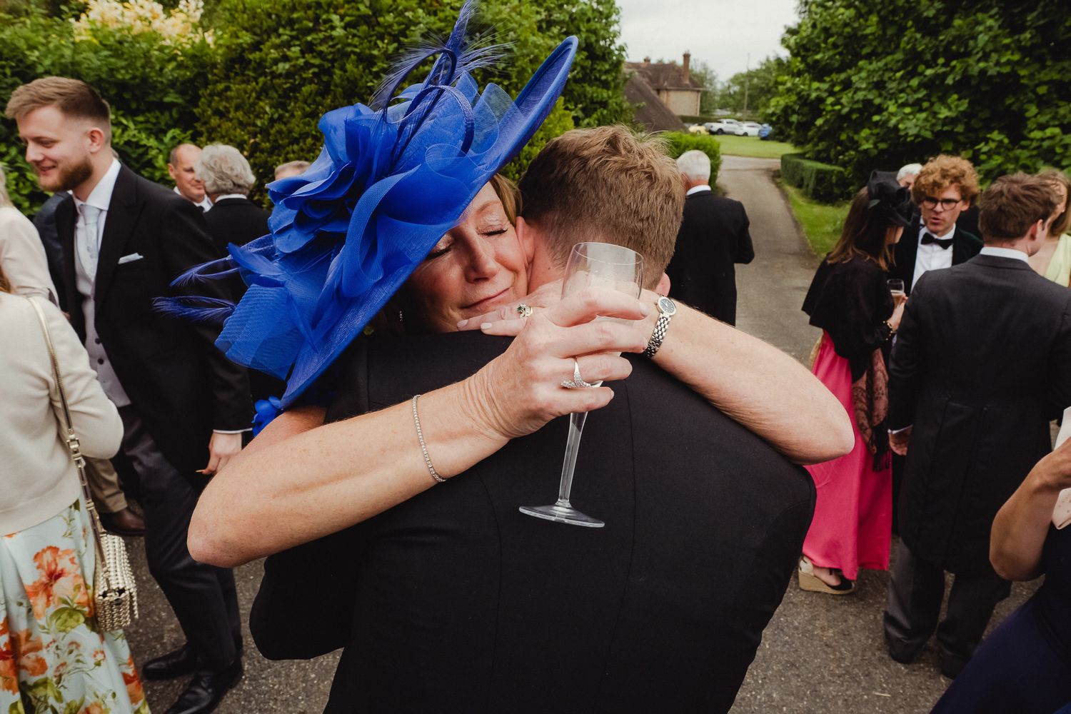 Two people share a celebratory dance move at an outdoor wedding reception surrounded by guests.