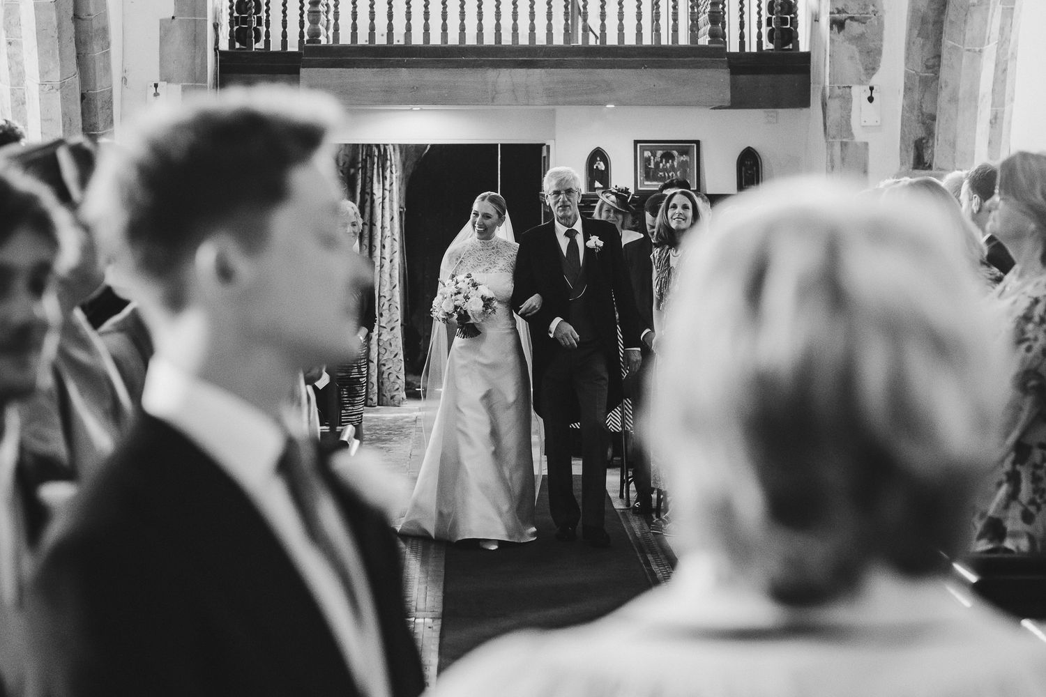 Black and white candid wedding reception photograph showing guests enjoying a dance floor moment at a celebration.