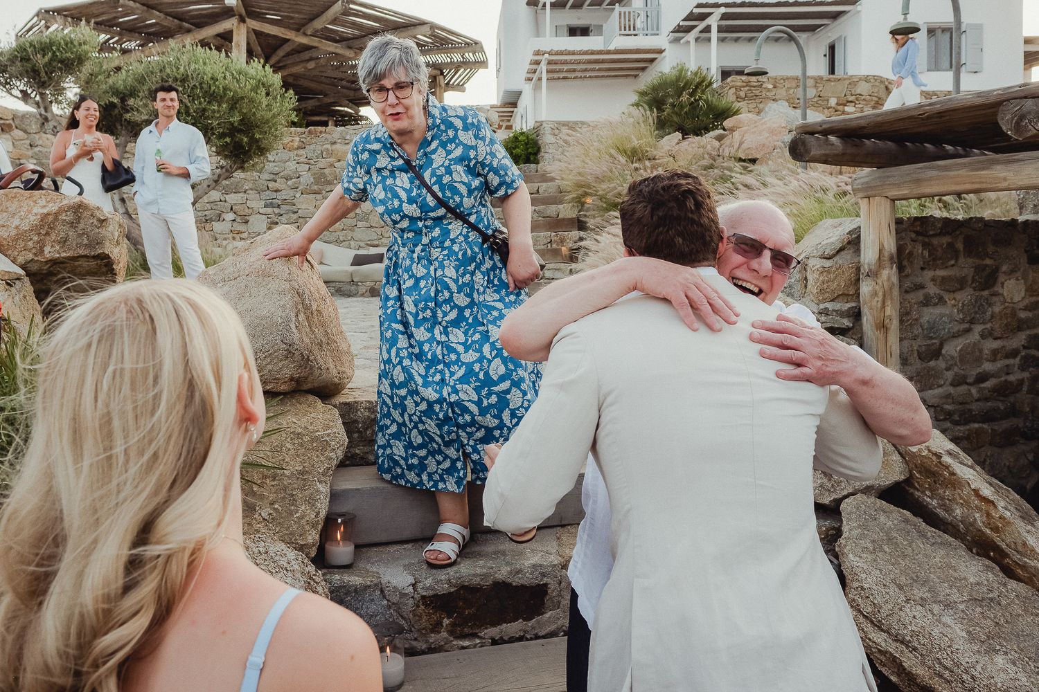 A couple shares tender moments on a rocky beach during a summer engagement photography session.