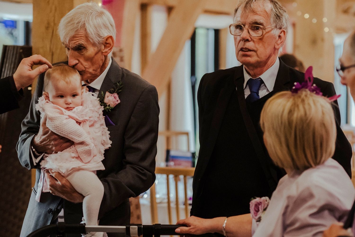 Senior gentlemen with baby at formal event in elegant venue.