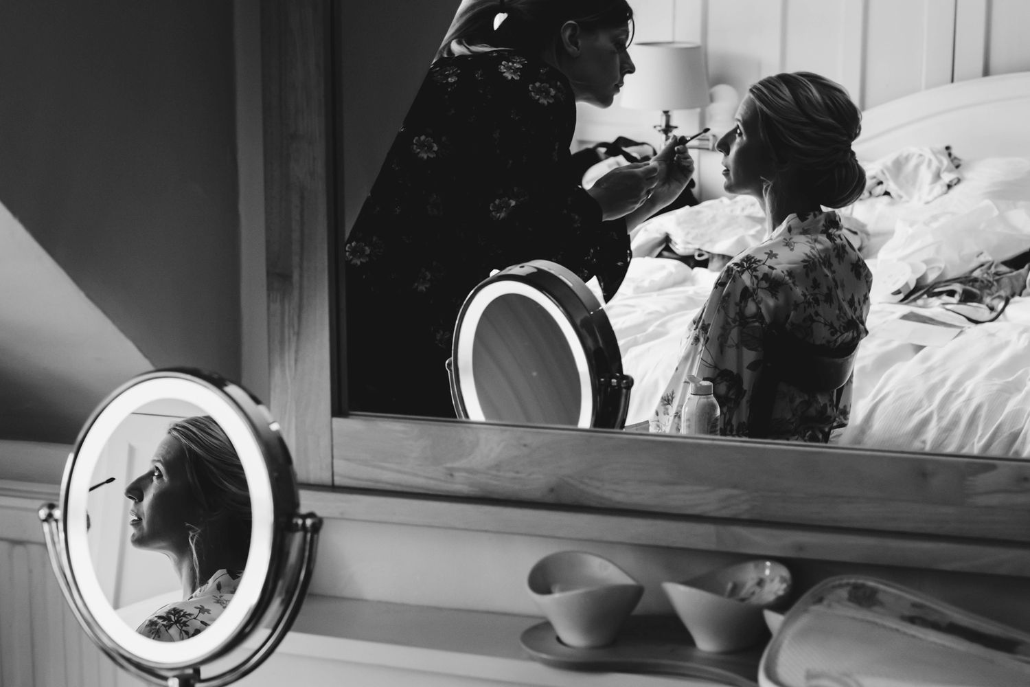A black and white reflection in a makeup mirror during wedding preparations.