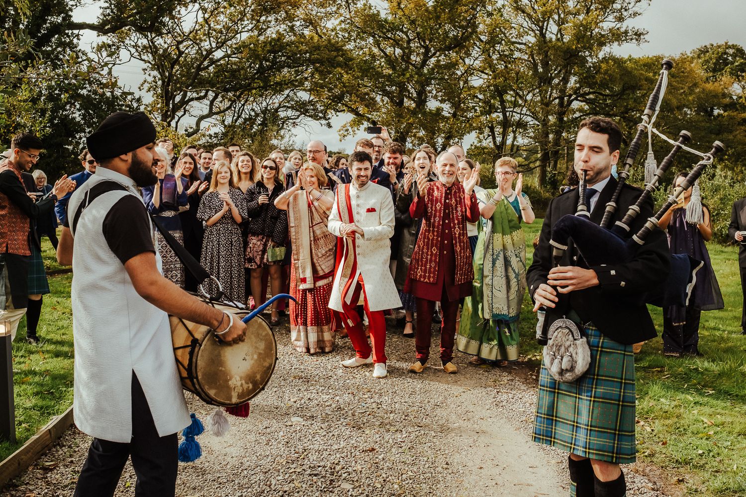 Bagpipers perform for wedding guests in traditional Scottish kilts during an outdoor ceremony.