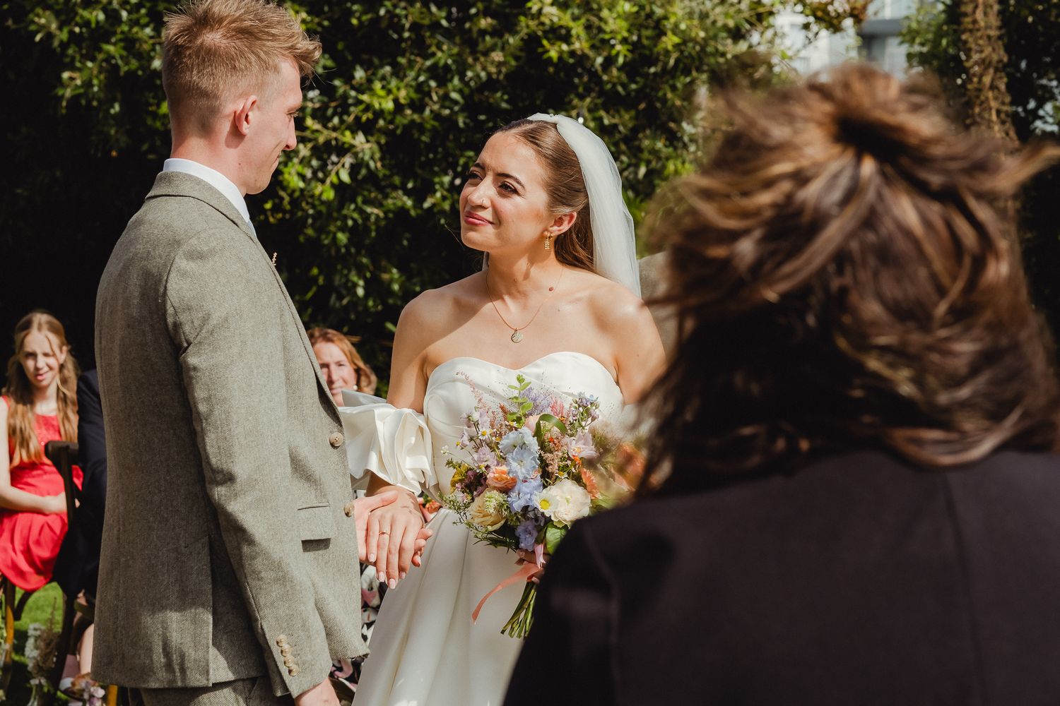 A couple shares a joyful moment together outdoors during their wedding ceremony on a sunny day.