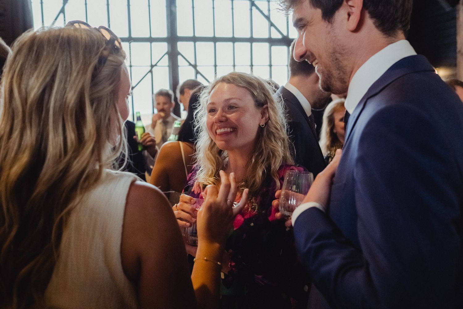 A group of people share a joyful moment of laughter at a social gathering indoors.