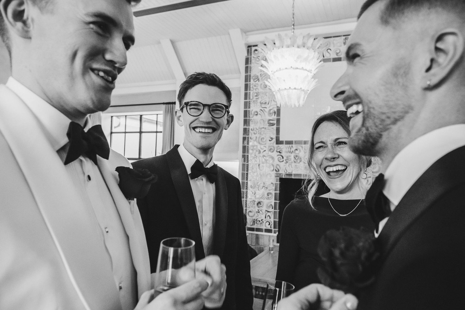 A black and white candid photo showing people engaged in lively conversation at a social gathering.