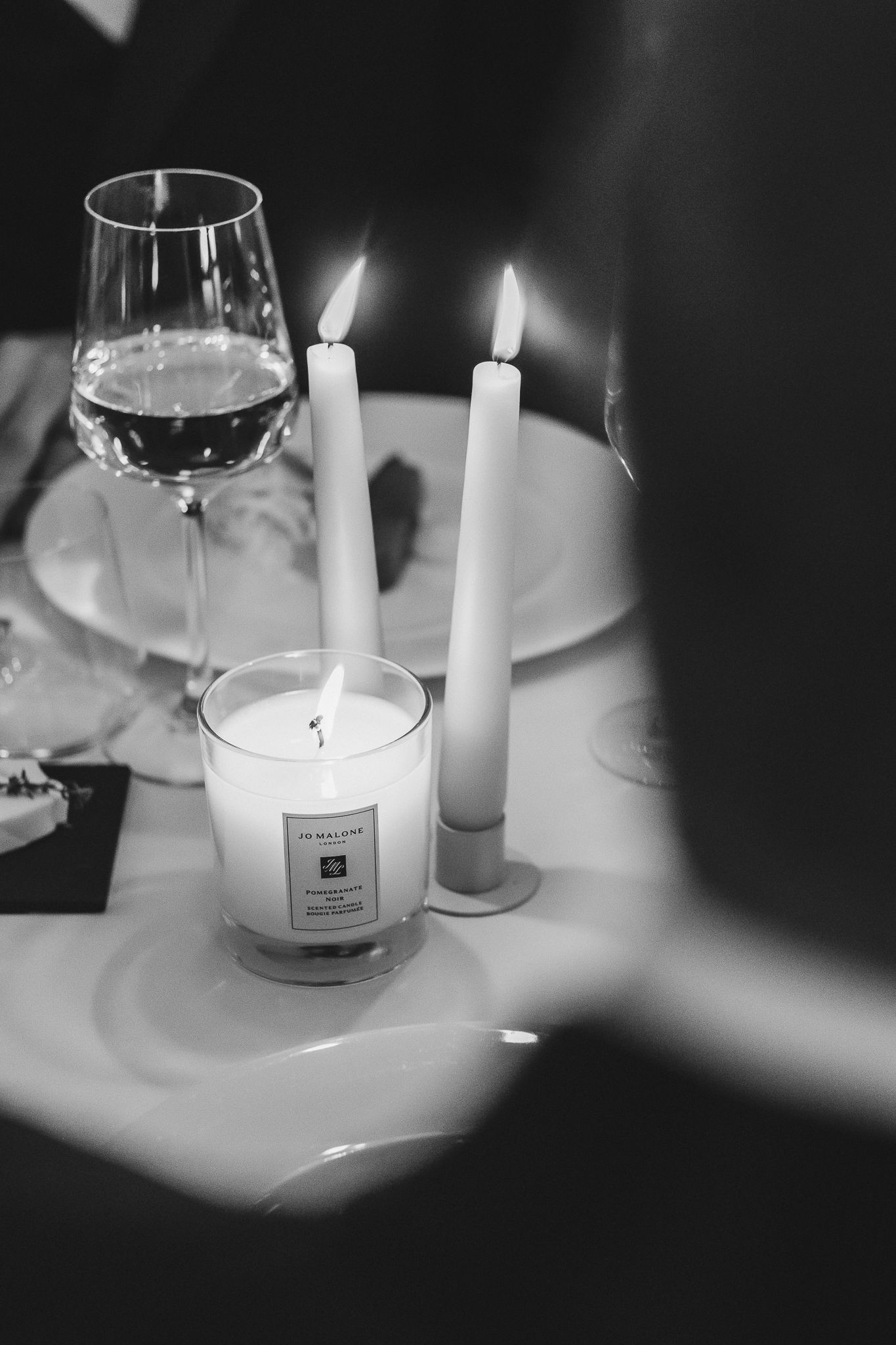 Black and white image of elegant table settings with lit candles and wine glasses creating a romantic ambiance.
