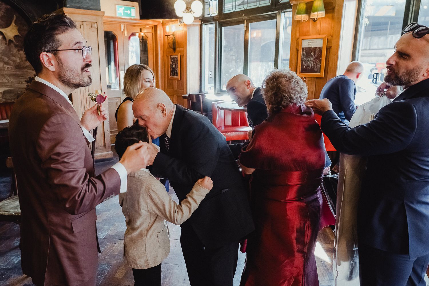 People dancing together in a social setting with warm lighting and wood paneled walls.