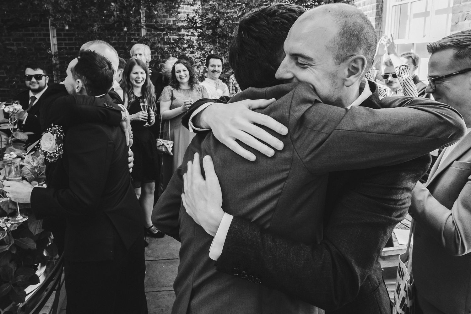 Black and white photos show emotional moments of people embracing at what appears to be a wedding celebration.