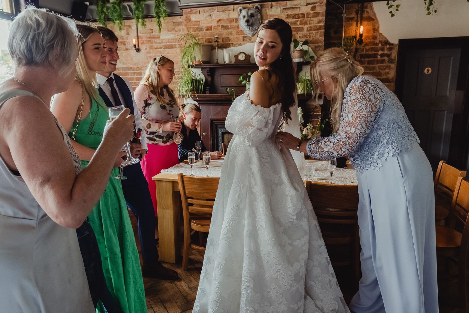 Wedding guests dancing and celebrating together at a reception venue with brick walls and festive atmosphere.