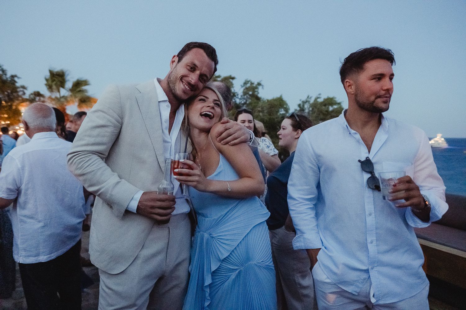 A series of candid photos showing people laughing and embracing at an outdoor gathering in blue attire.