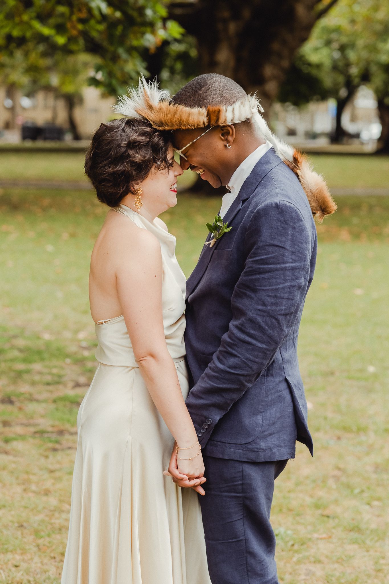 A couple shares an intimate moment during their outdoor wedding ceremony in a park setting.