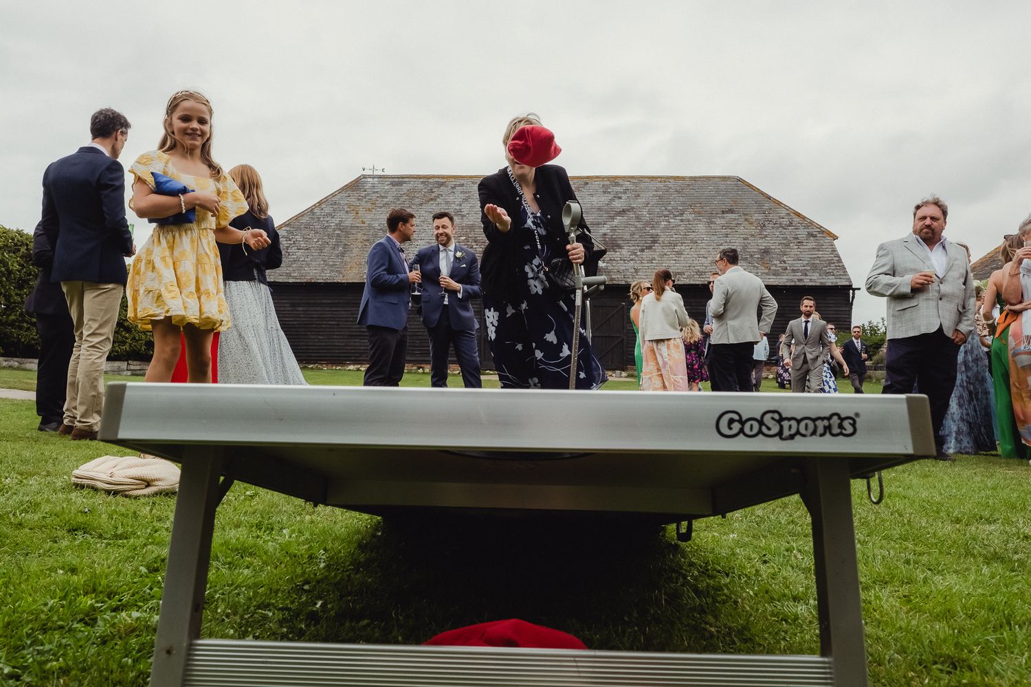 Wedding guests gather on a grassy lawn for an outdoor celebration under cloudy skies.