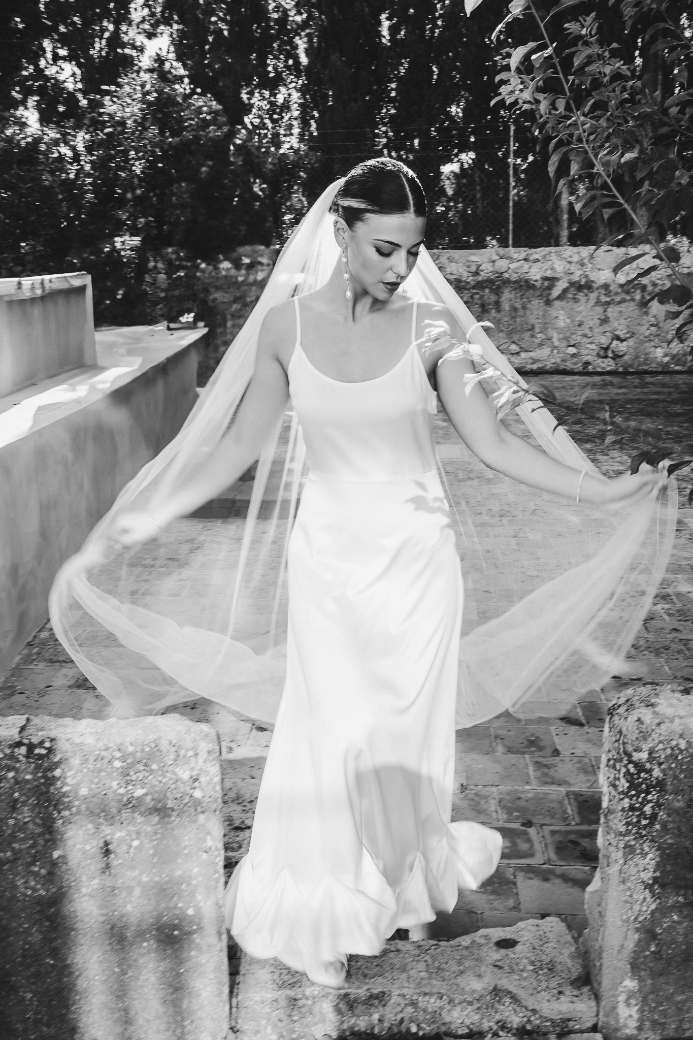 A figure in a flowing white dress dances gracefully in a garden setting, creating an ethereal and dreamy atmosphere.