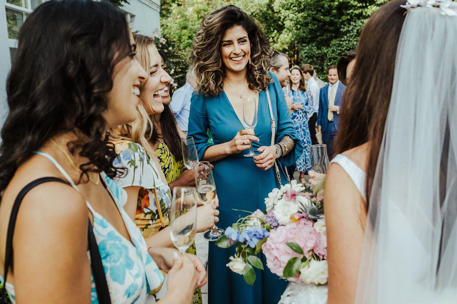 Wedding guests socializing at an outdoor reception with floral decorations.
