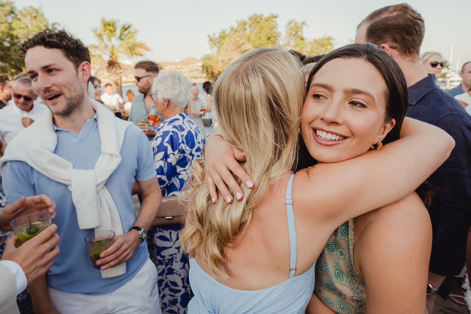 People hugging and celebrating at an outdoor event during golden hour.