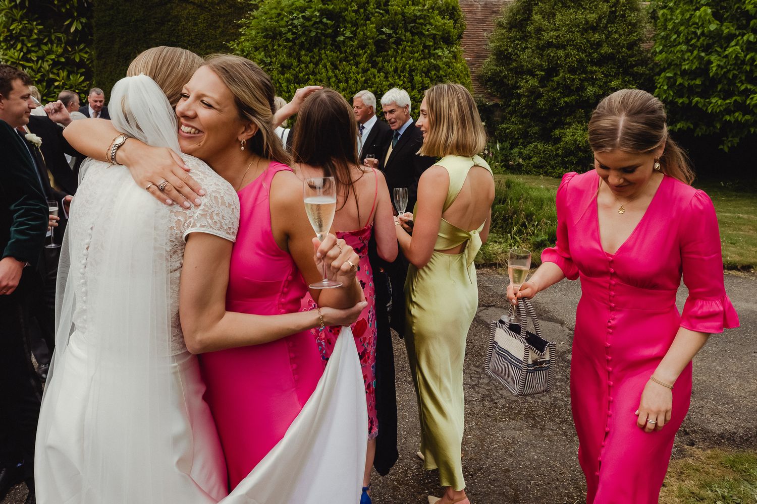 Guests in pink and light-colored dresses dancing and celebrating at an outdoor summer party or wedding reception.