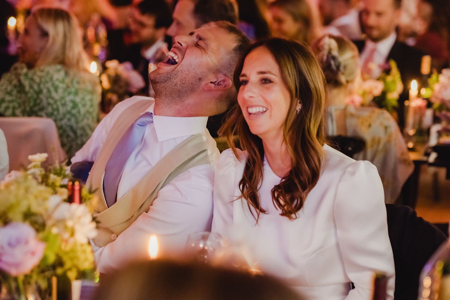 Wedding guests dancing and celebrating at a lively reception with warm lighting and festive atmosphere.