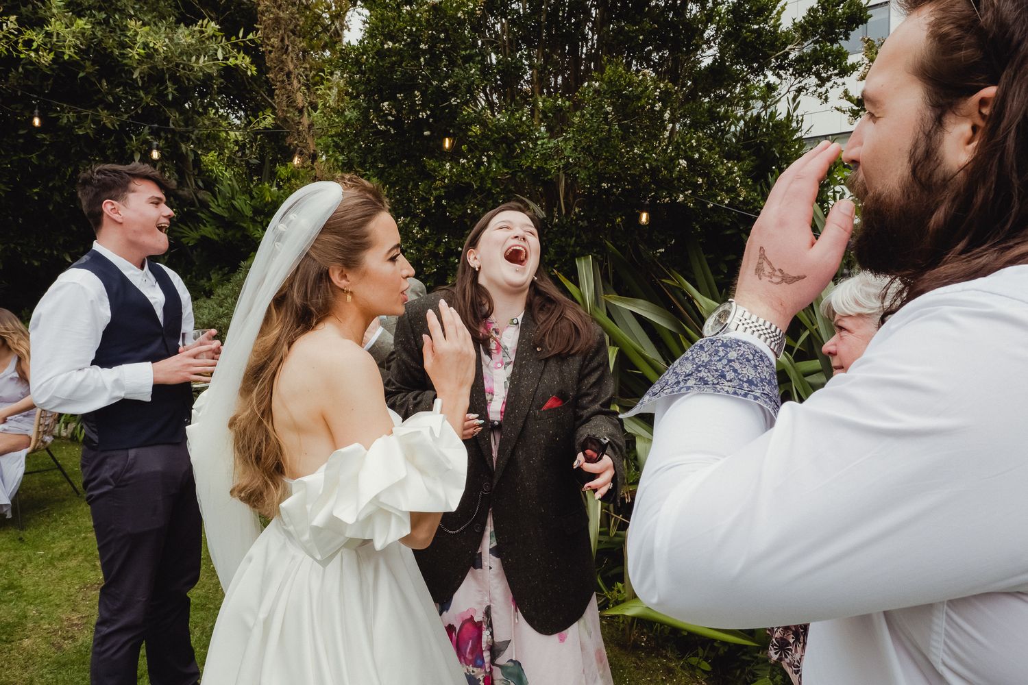 A candid moment of laughter and joy captured during an outdoor wedding celebration in a garden setting.