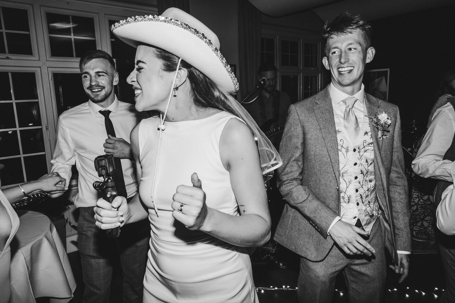 Black and white photo of wedding guests dancing and mingling at an evening celebration.