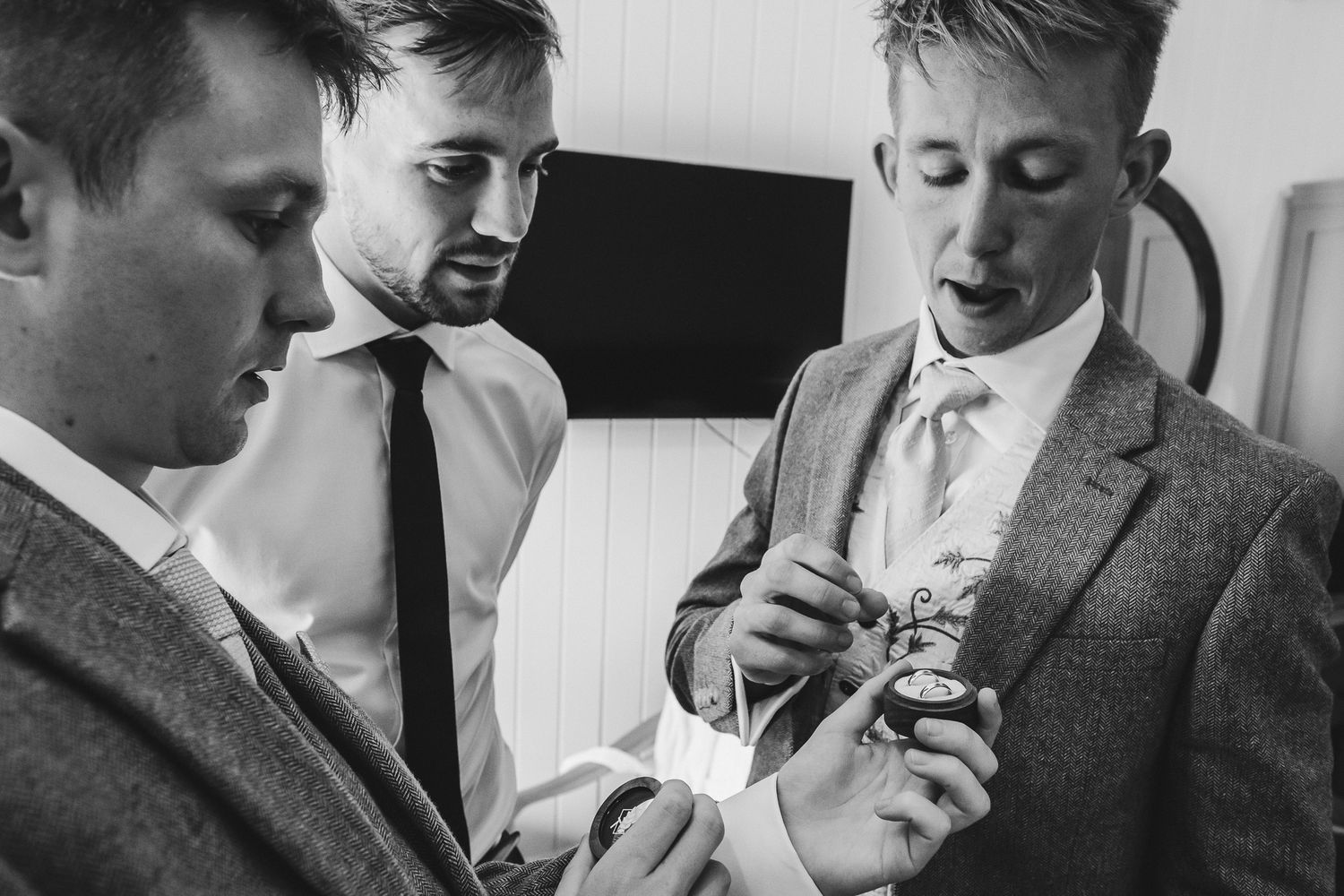 A series of black and white wedding photos showing groomsmen getting ready and adjusting their formal attire.