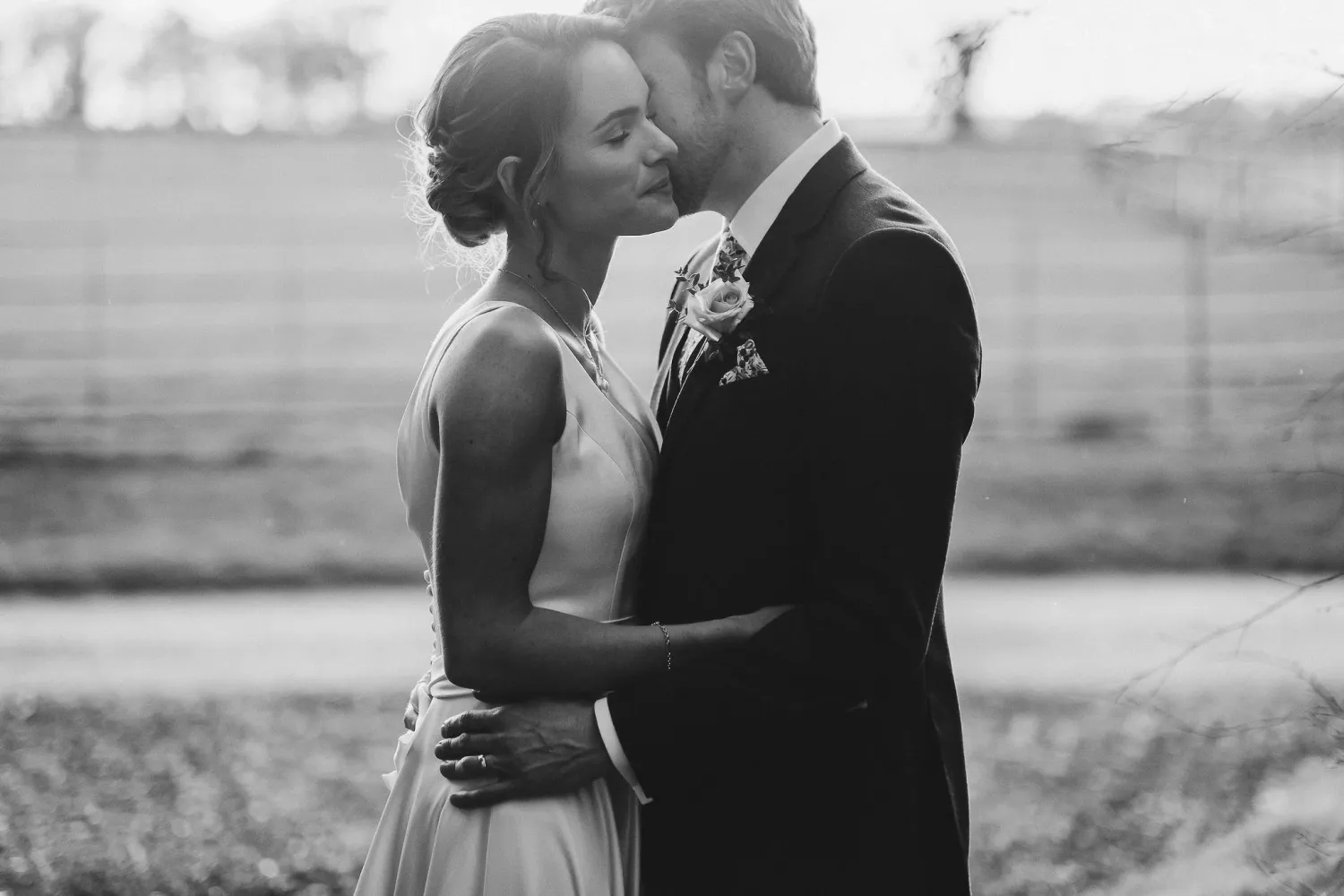A couple embraces in an intimate moment during their outdoor wedding photoshoot at sunset.