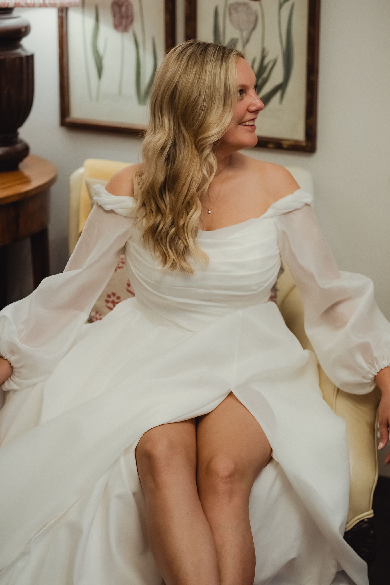 Close-up details of an elegant white wedding dress with dramatic off-shoulder ruffles and flowing fabric.