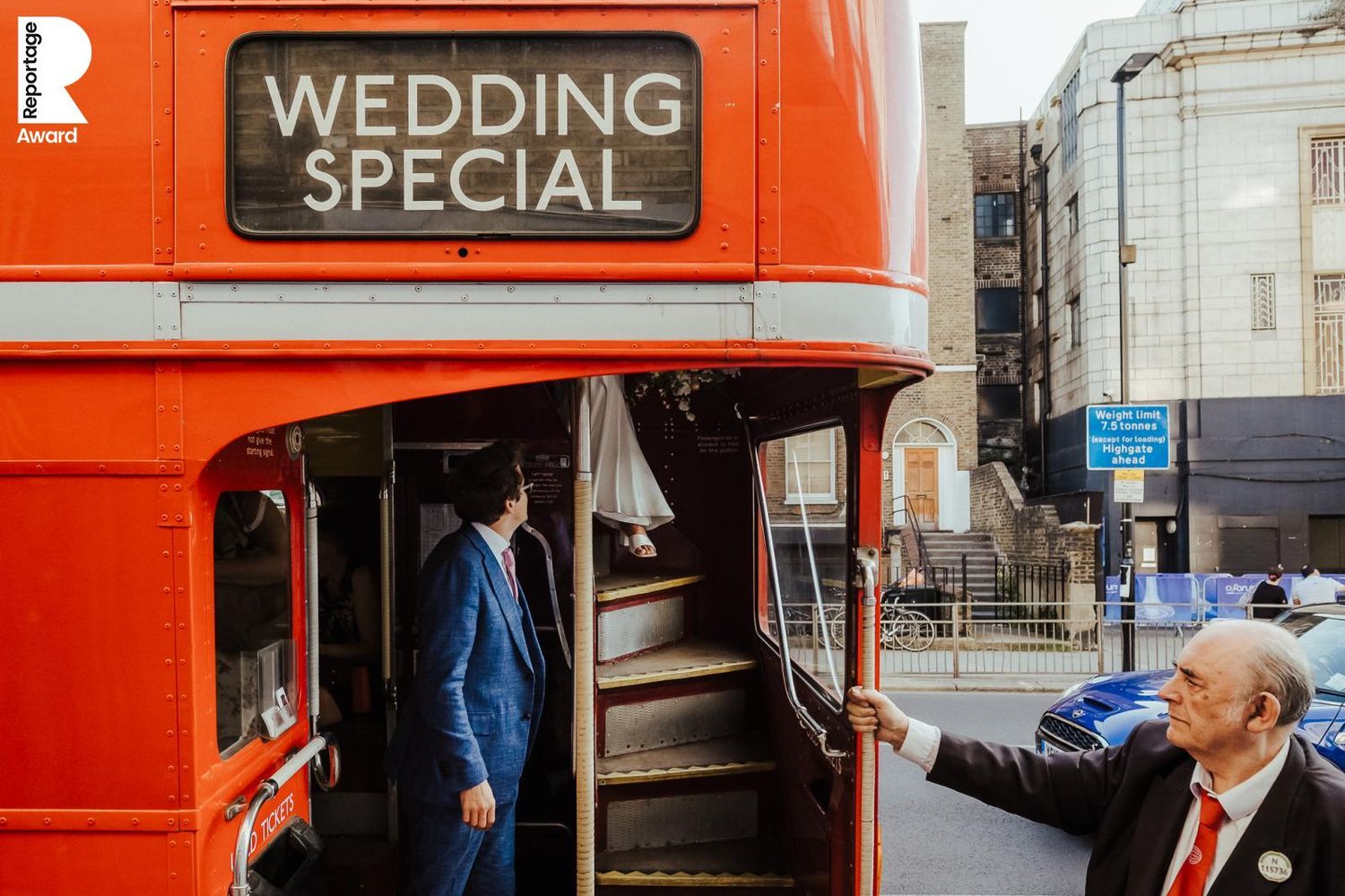 Red double decker bus with 'Wedding Special' sign parked outside a historic building.