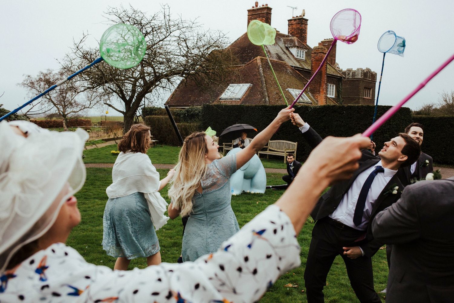 Wedding guests blowing bubbles outdoors with a rustic house in the background.