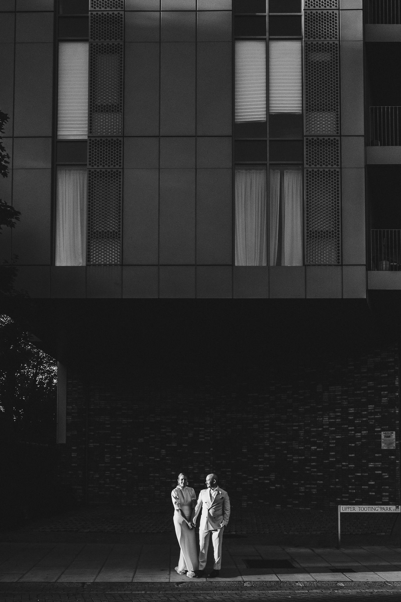 A series of architectural frames show two figures in white clothing walking together against a modern building facade.