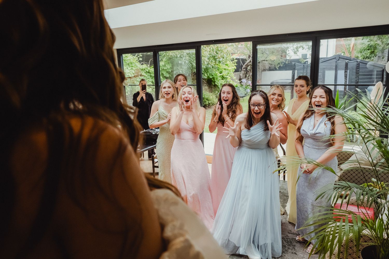 A group of people in pink and blue dresses gather together at what appears to be a wedding celebration.