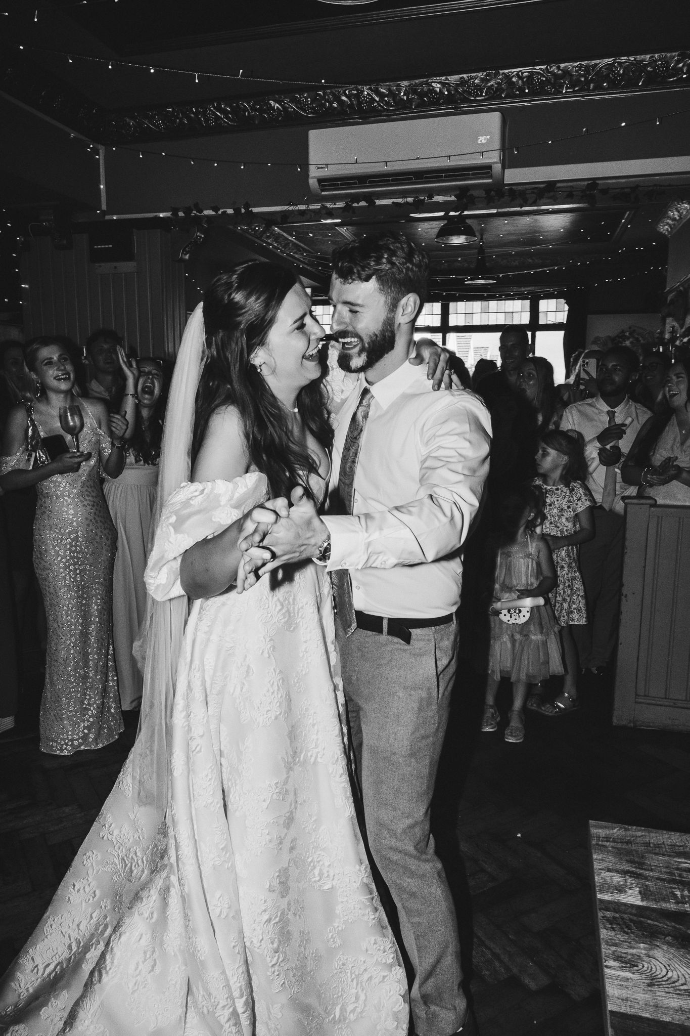 Couples dancing together at a vintage wedding reception in formal attire on a crowded dance floor.