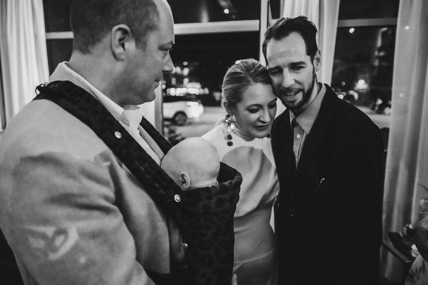 A group gathered at what appears to be a wedding reception, enjoying drinks and conversation in an evening setting.