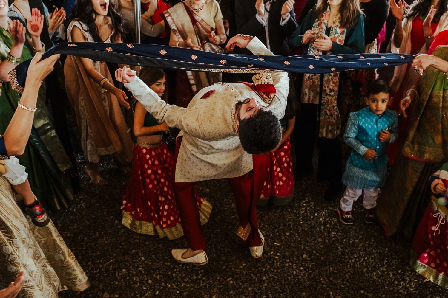Wedding guests performing traditional dance moves under a tent during reception celebrations.
