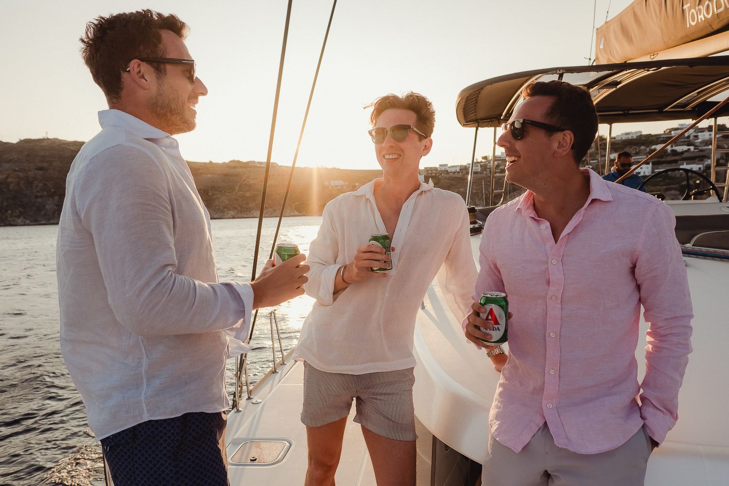 A group enjoying drinks and conversation while sailing on a yacht at sunset.