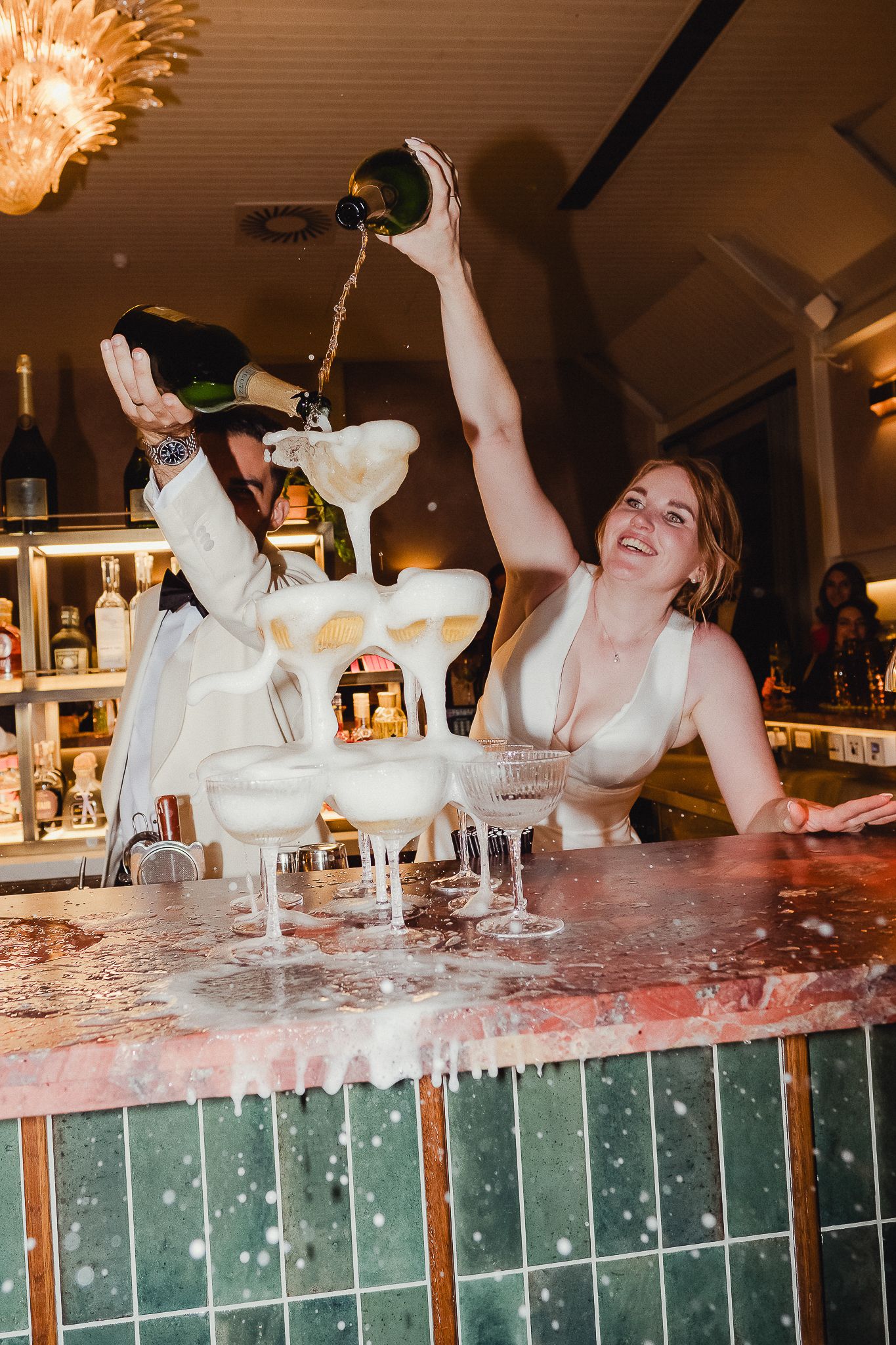 Sequence of bartenders performing flair tricks behind a bar counter with cocktail glasses and bottles.