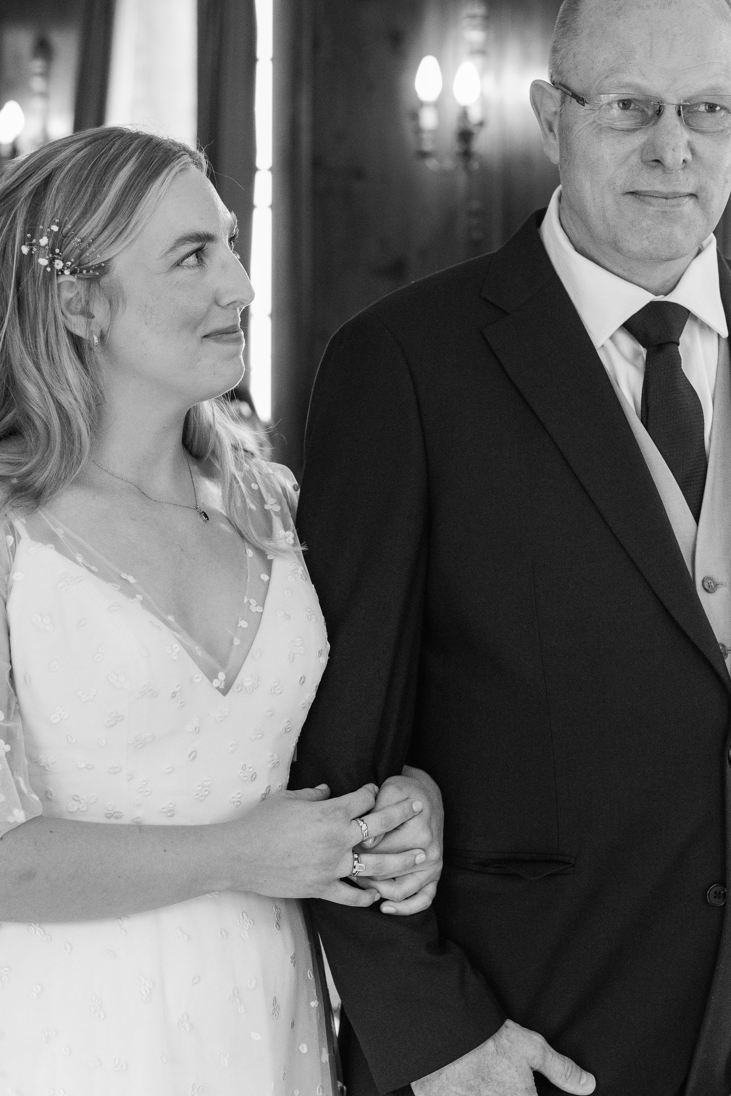 Black and white photo of a bride in a delicate beaded wedding dress and hair accessory smiling up at a man in a dark suit and tie.