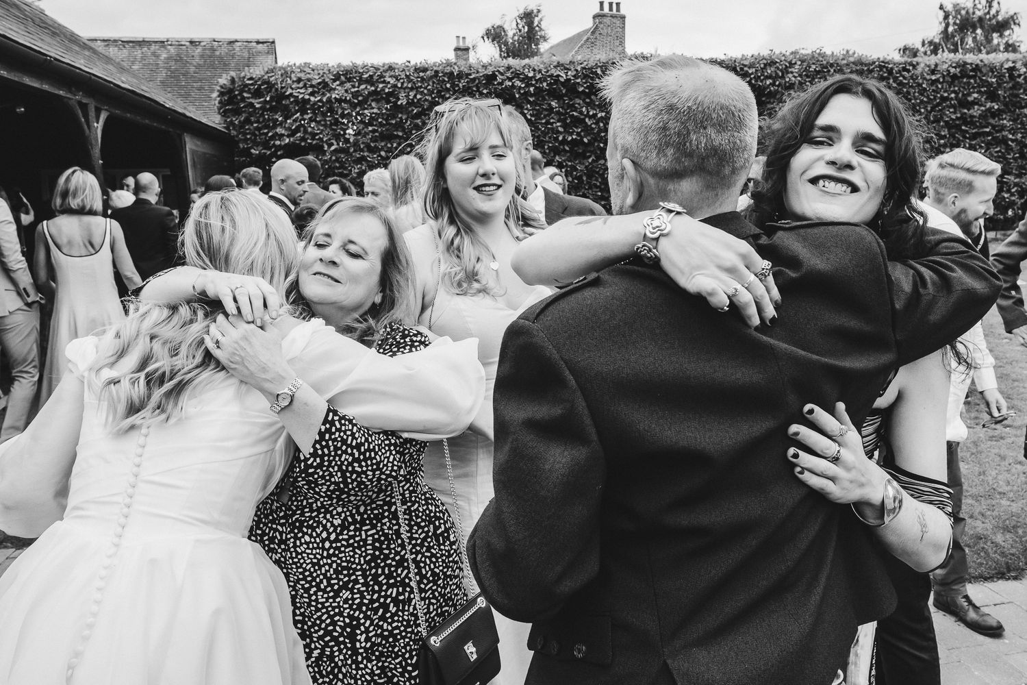 Black and white wedding photo collage showing guests hugging and embracing during reception celebrations.