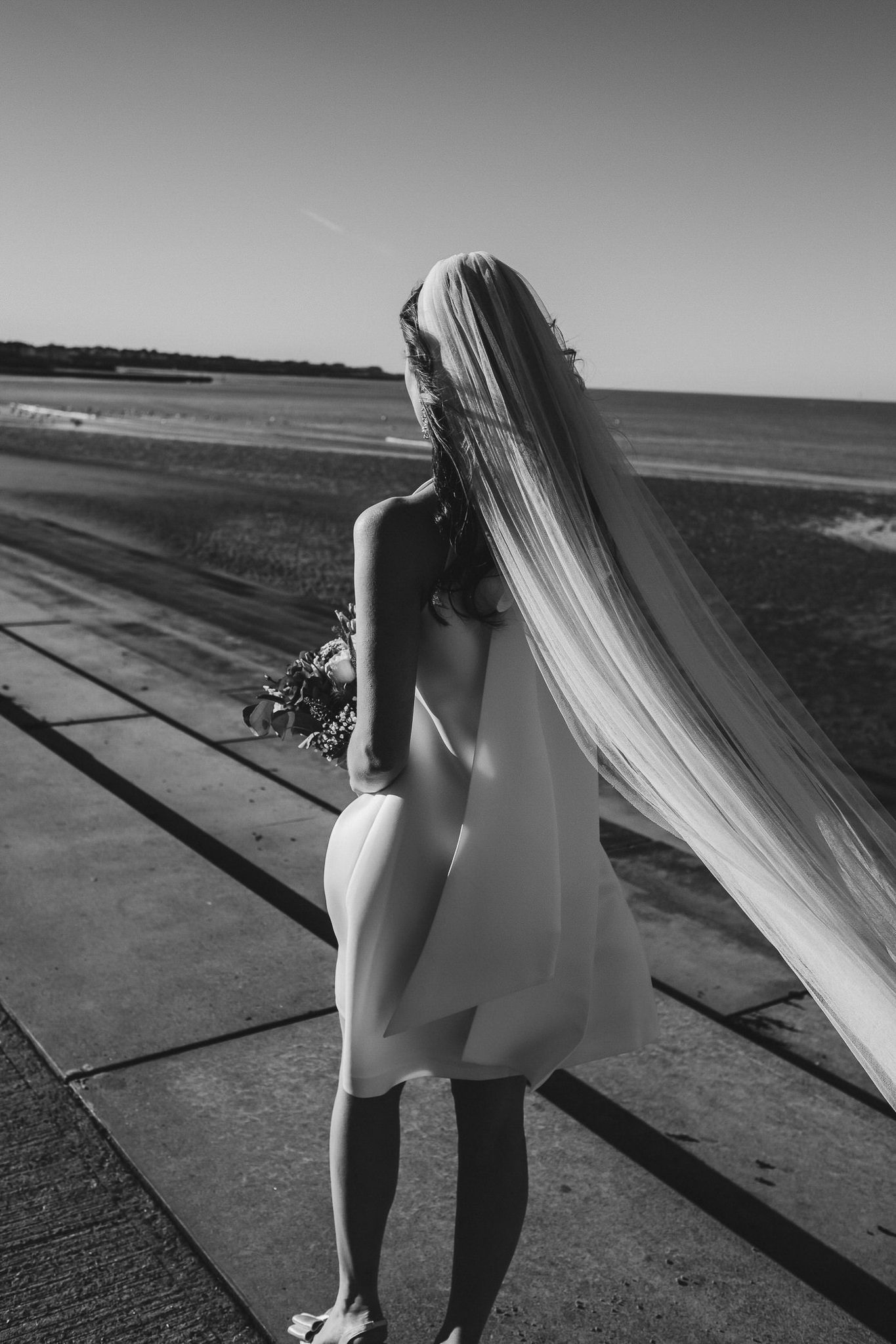 A black and white photo sequence shows a person in white walking along a path with flowing fabric in the wind.