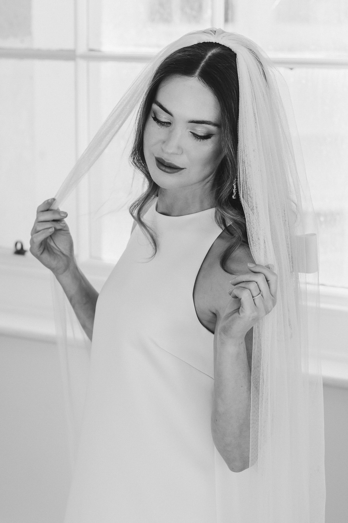 A bride in a white wedding dress and veil poses elegantly in a series of black and white portraits.