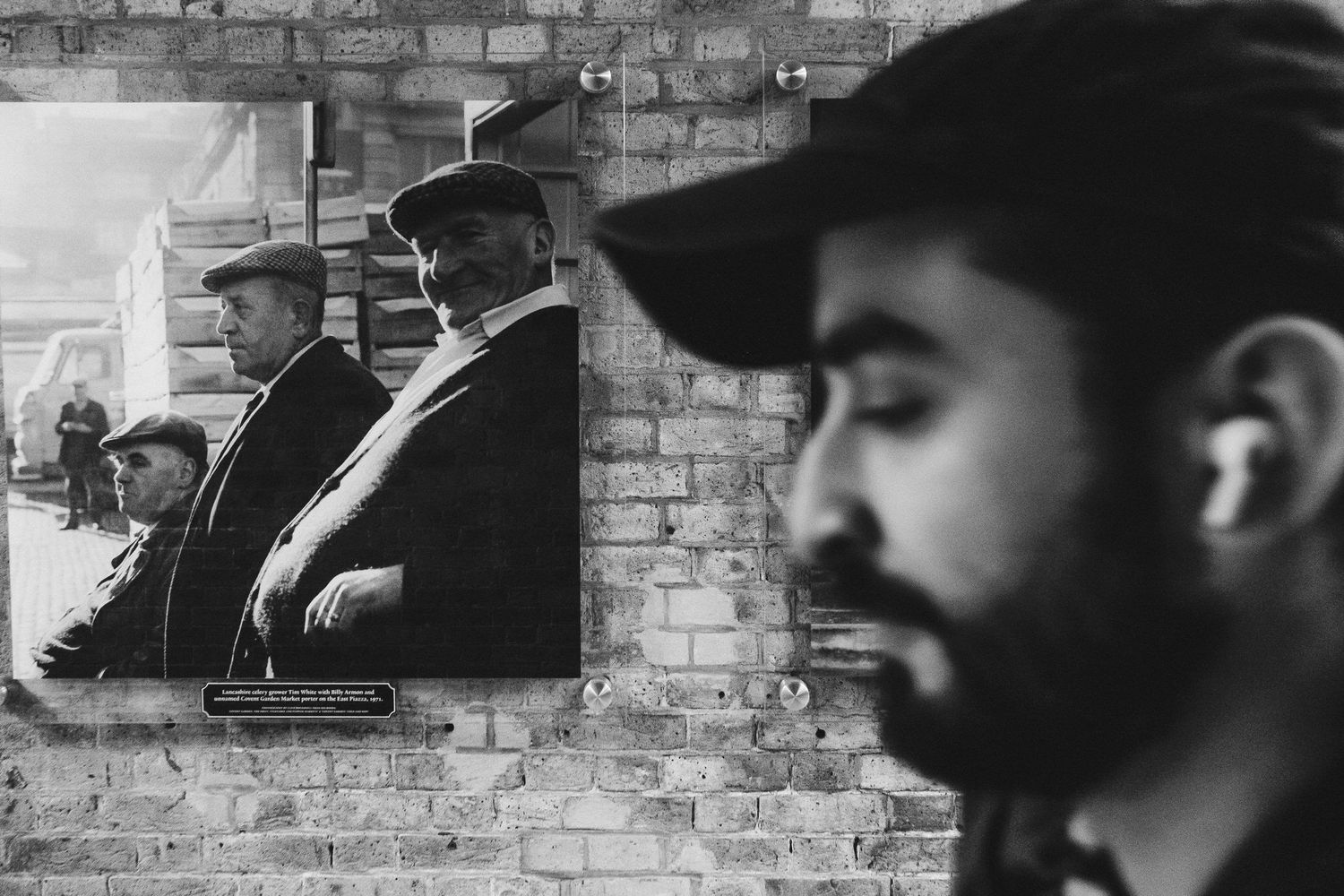Black and white artistic portrait showing a person's silhouette against mirrors on a brick wall.