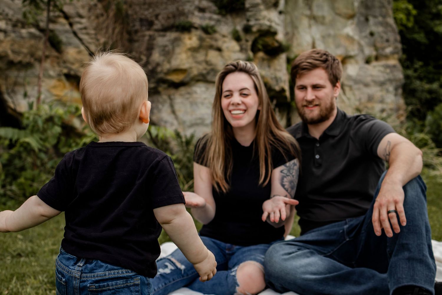 Relaxed family portrait session against stone wall backdrop outdoors.