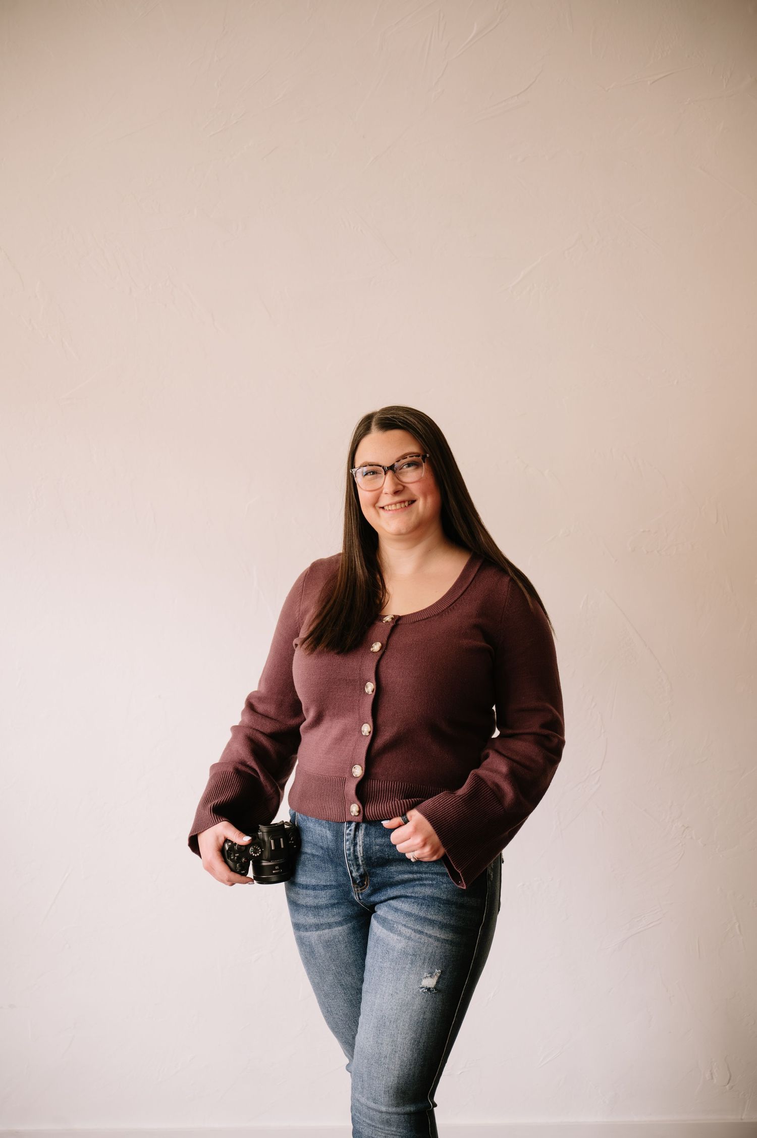Woman in brown cardigan and jeans poses against neutral wall showing casual style outfit from different angles.