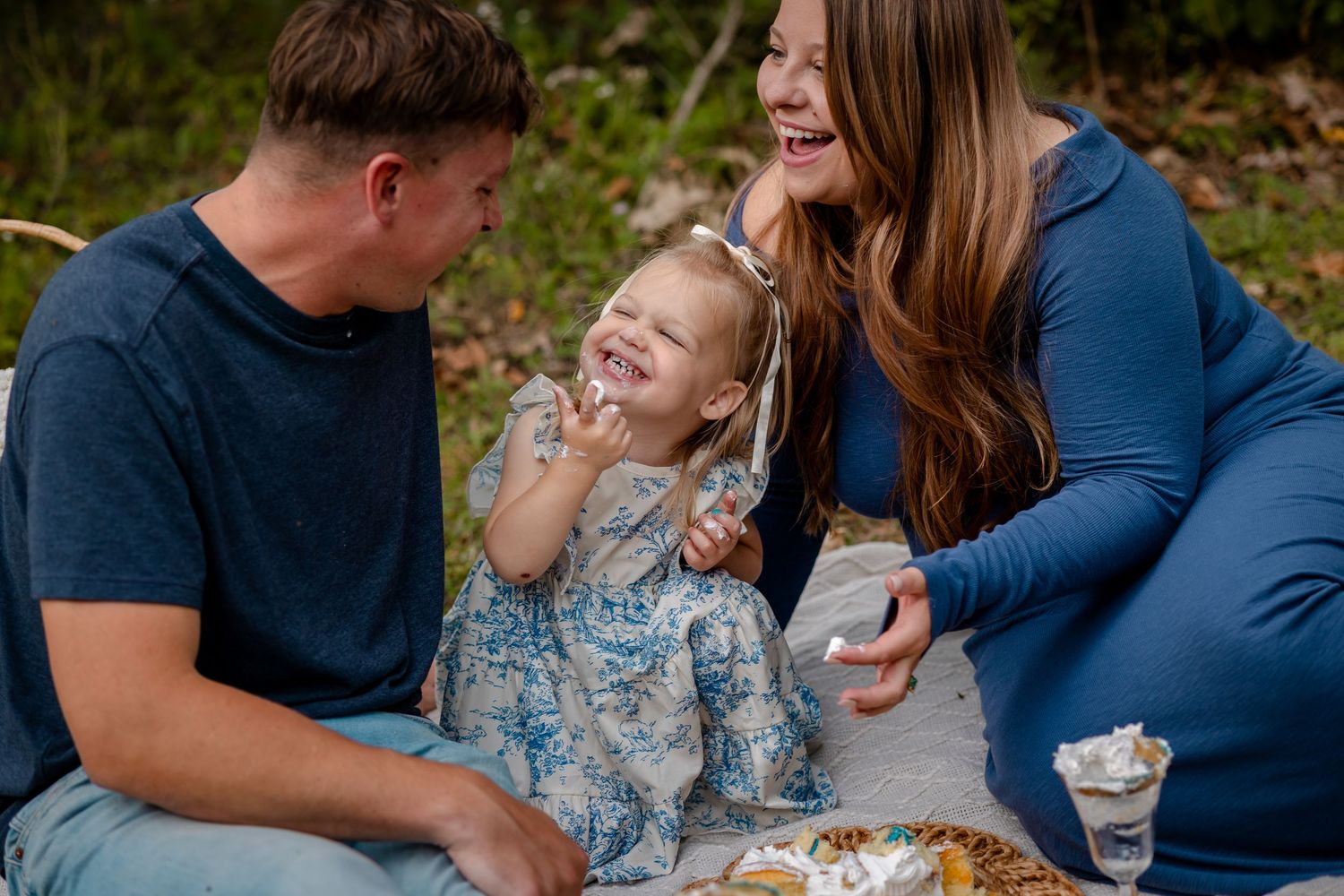 A family enjoys a picnic outdoors together on a sunny autumn day, sharing laughter and snacks.